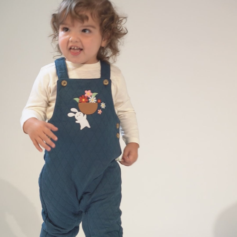 
                      
                        Load and play video in Gallery viewer, Toddler in teal quilted overalls with a bunny and flower embroidery, wearing brown leather shoes.
                      
                    