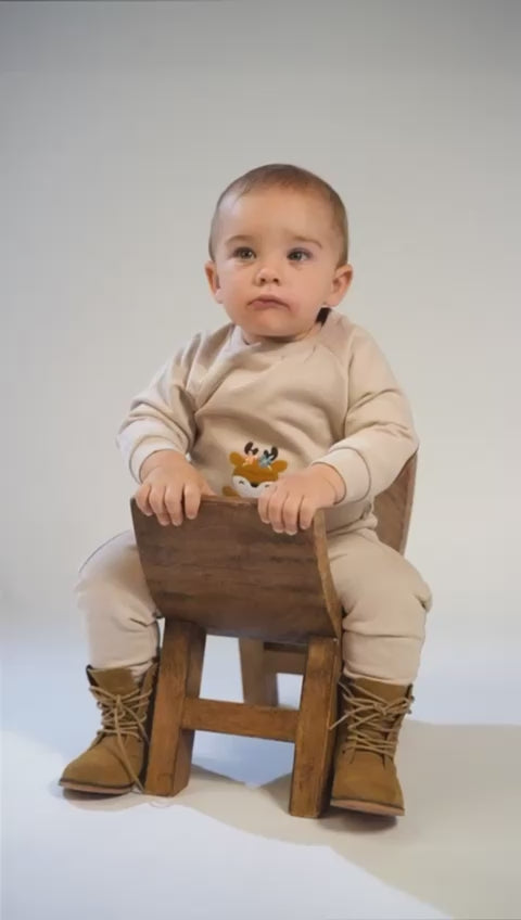 Baby in an olive-green quilted tracksuit with a red car and brown bear embroidery.