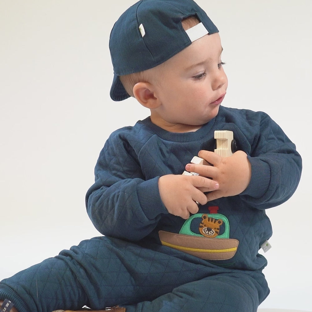 
                      
                        Load and play video in Gallery viewer, Baby in a teal sweatshirt and pants with a tiger-ship applique, navy baseball cap, and brown boots.
                      
                    